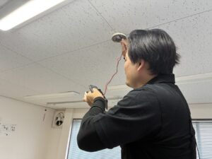名古屋市で火災感知器の誤作動原因を調査するためテスターで電圧を確認する作業