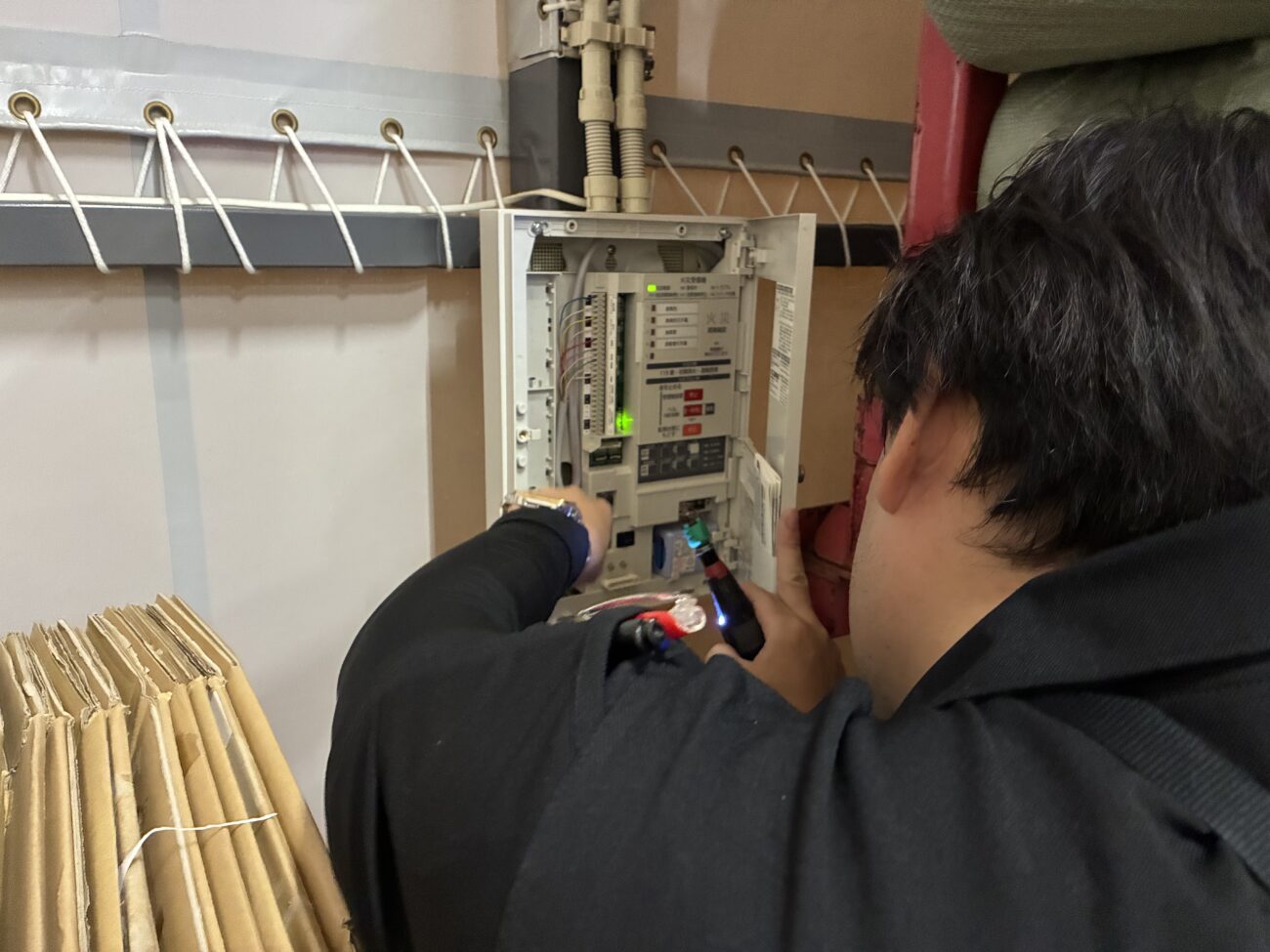 小牧市の物流倉庫で火災受信機の誤作動による警報音を緊急調査する消防設備点検